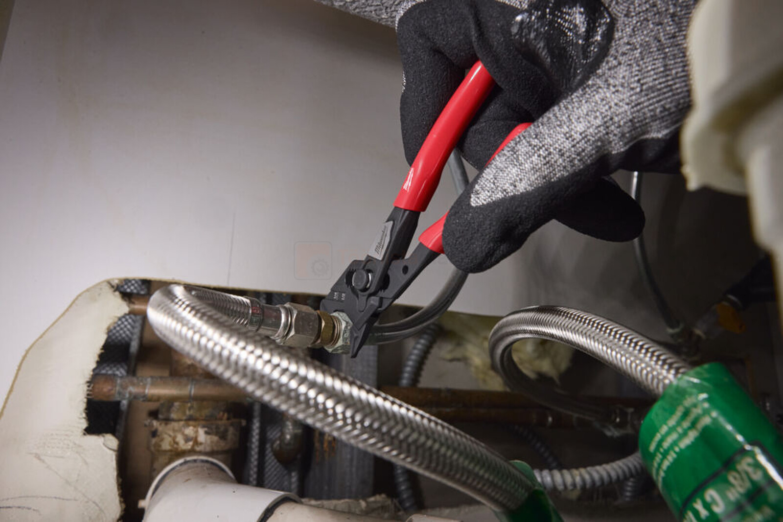 Pildil on näha, kuidas inimene kasutab Milwaukee siledate lõugadega veepumbatange, et töötada torustikuga.